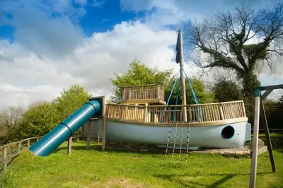a playground with a boat and a slide at Saffir Luxury Eco Lodge, log-fired bath & views in Dihewid