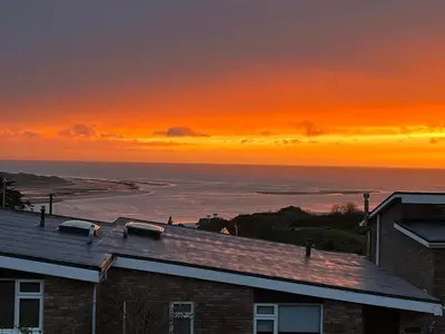 a sunset view of the ocean from a house at Terrace by the Tide in Aberdyfi