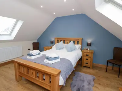 a bedroom with a large bed with blue walls at Beudy in Aberystwyth