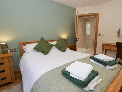 a bedroom with a white bed with green towels on it at Beudy in Aberystwyth