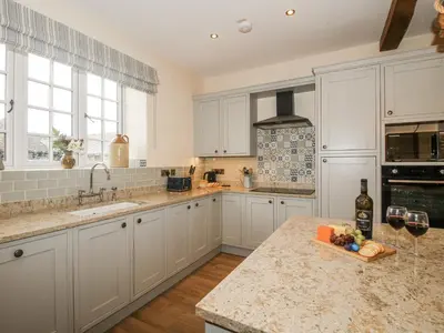 a kitchen with white cabinets and a counter with wine glasses at Highfields Farm in Church Stretton