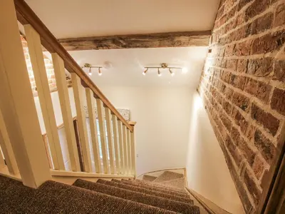 a staircase in a home with a brick wall at Highfields Farm in Church Stretton