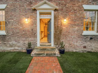 a brick house with a yellow door and stairs at Highfields Farm in Church Stretton
