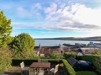 a patio with a table and chairs and a view of the water at Zenobia in New Quay