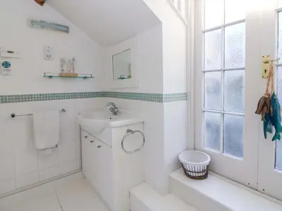 a white bathroom with a sink and a toilet at Zenobia in New Quay