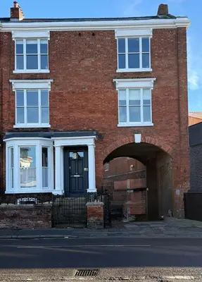 a red brick house with a black door and an archway at Luxury Apartment in Shropshire sleeps 4 in Shrewsbury