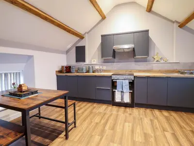 a kitchen with blue cabinets and a wooden table at Clegir Bach in Corwen