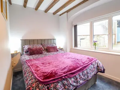 a bedroom with a large bed and two windows at Clegir Bach in Corwen