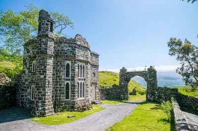 an old stone building with a bridge in the background at Hywel-Sele-Lodge in Llanfachreth
