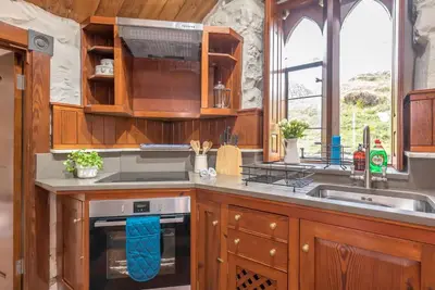 a kitchen with wooden cabinets and a sink at Hywel-Sele-Lodge in Llanfachreth