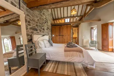 a bedroom with a large bed and a stone wall at Hywel-Sele-Lodge in Llanfachreth