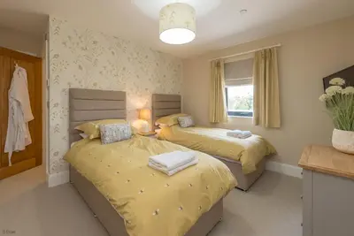 two beds in a bedroom with yellow sheets at Llety-Cariad in Montgomery