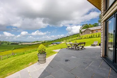a patio with a picnic table and a view of a field at Llety-Bugail in Montgomery