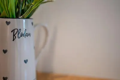 a white vase with a bouquet of flowers in it at Llety-Bugail in Montgomery