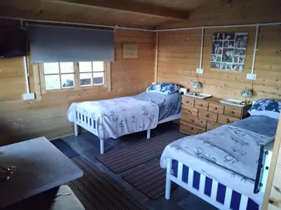 two beds in a room with wooden walls at Moonlight View in Newtown