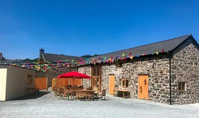 a stone building with a table and a red umbrella at The Kings Head, Meifod in Meifod