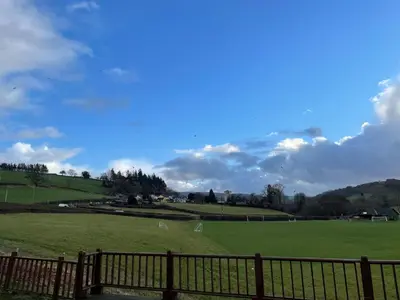 a large green field with a wooden fence at Swn yr Coed in Sennybridge