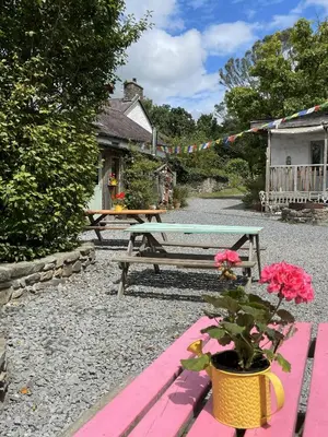 a picnic table with flowers in front of a house at Naturesbase Lodge in Cilcennin