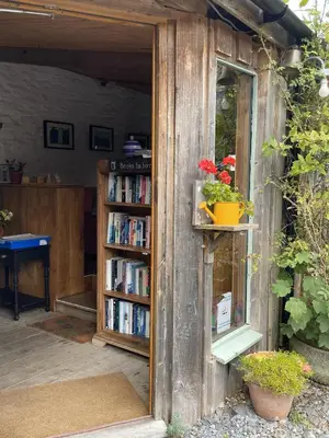 a book shelf filled with books next to a window at Naturesbase Lodge in Cilcennin