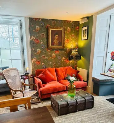 a living room with a red couch and a painting at Y Meirionnydd Boutique Hotel in Dolgellau