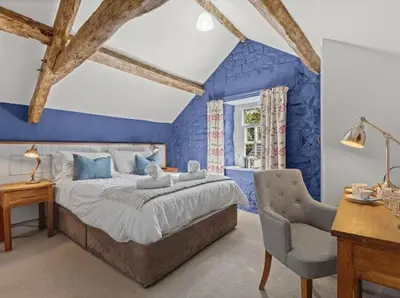a bedroom with blue walls and a bed and a chair at Y Meirionnydd Boutique Hotel in Dolgellau