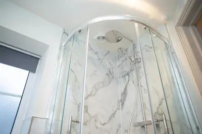 a bathroom with a shower with a marble wall at Dolphin View New Quay in New Quay