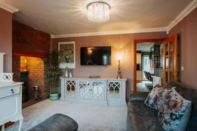 a living room with a couch and a tv on a wall at Cherry Tree House in Shrewsbury