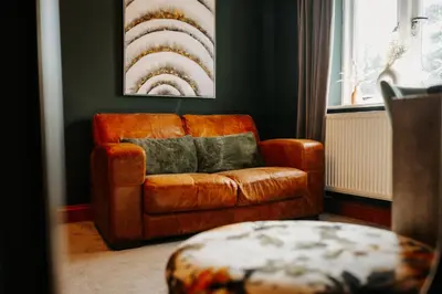 a brown leather couch in a living room with a painting at Cherry Tree House in Shrewsbury