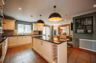 a kitchen with white cabinets and black counter tops at Cherry Tree House in Shrewsbury