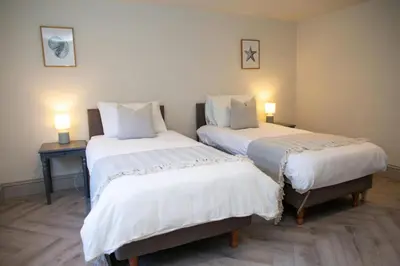 two beds in a room with two tables and two lamps at Bay View New Quay in New Quay