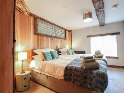 a bedroom with a large bed with blue pillows at Godre'r Gyrn, Plas Moelfre Hall Barns in Oswestry