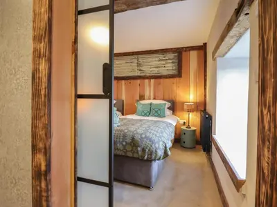 a bedroom with a bed and a mirror at Godre'r Gyrn, Plas Moelfre Hall Barns in Oswestry