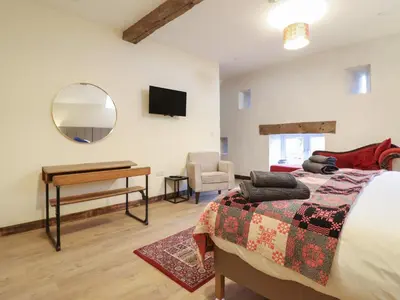 a bedroom with a bed and a desk and a mirror at Godre'r Gyrn, Plas Moelfre Hall Barns in Oswestry