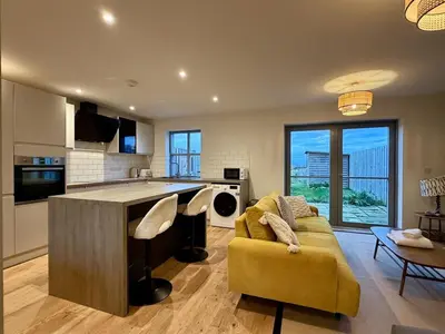 a living room with a yellow couch and a kitchen at Woodland View House in Norton Canon