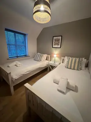 a bedroom with two beds and a chandelier at Woodland View House in Norton Canon