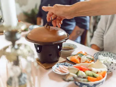a person is stirring a pot on a table with food at Belmont House in Hay-on-Wye