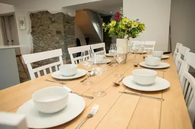 a wooden table with white dishes and wine glasses at Gelli Genlas Aberaeron in Llanarth
