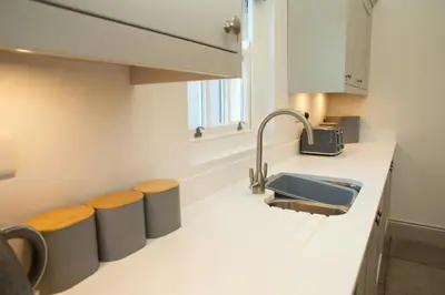 a kitchen with a sink and a counter with stools at Gelli Genlas Aberaeron in Llanarth