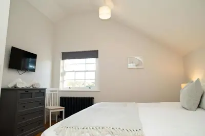 a bedroom with a bed and a dresser and a window at Gelli Genlas Aberaeron in Llanarth
