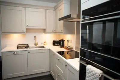 a white kitchen with white cabinets and a sink at 5 Rock Street New Quay in New Quay