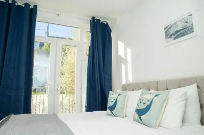 a bedroom with a bed with blue curtains and a window at 5 Rock Street New Quay in New Quay