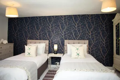 a bedroom with two beds and a blue wall at 5 Rock Street New Quay in New Quay