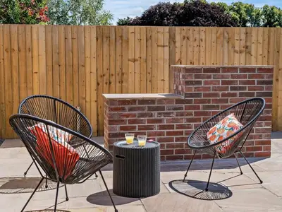 two chairs and a trash can next to a brick wall at 3 Bed in Brecon oc-92341 in Brecon