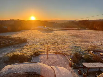 a snowy field with the sunset in the background at Nant Hafren Retreat in Llanwnog