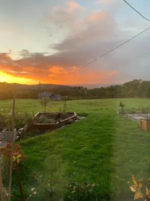 a field of grass with a sunset in the background at Nant Hafren Retreat in Llanwnog