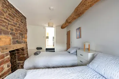 two beds in a bedroom with a brick wall at Finest Retreats - Brecon House in Builth Wells