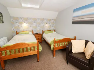 two beds in a room with a chair and a couch at Old Farmhouse Cottage in New Quay