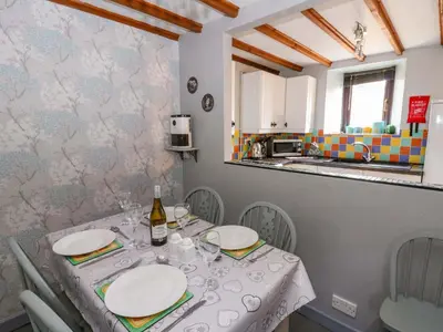 a dining room with a table and a kitchen at Old Farmhouse Cottage in New Quay