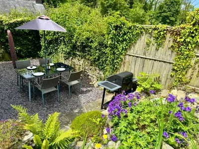 a garden with a table and chairs and an umbrella at Old Farmhouse Cottage in New Quay