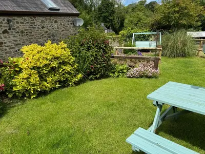 a picnic table in a yard with flowers at Old Farmhouse Cottage in New Quay